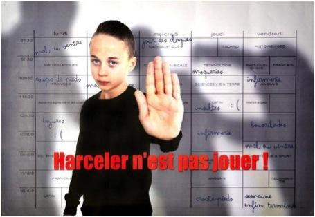 Campagne anti-harcèlement ("Harceler n'est pas jouer!") Un jeune garçon vu en buste et vêtu de noir, tend en avant la main gauche qui apparaît en gros plan. En rouge le slogan "Harceler n'est pas jouer!"