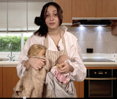 Une jeune fille, l'air épuisée, avec deux poupons/bébés dans les bras dans sa cuisine